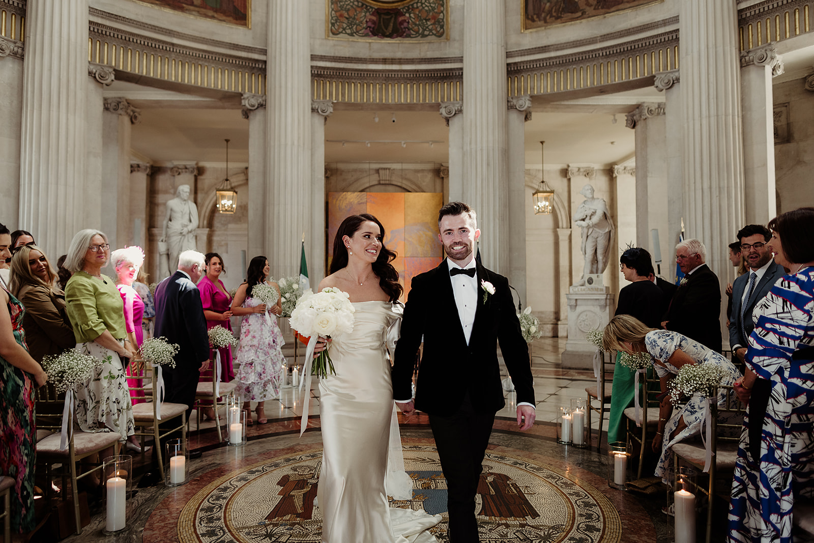 Laoise and Ultan walking back down the aisle at Dublin City Hall as their guests applaud