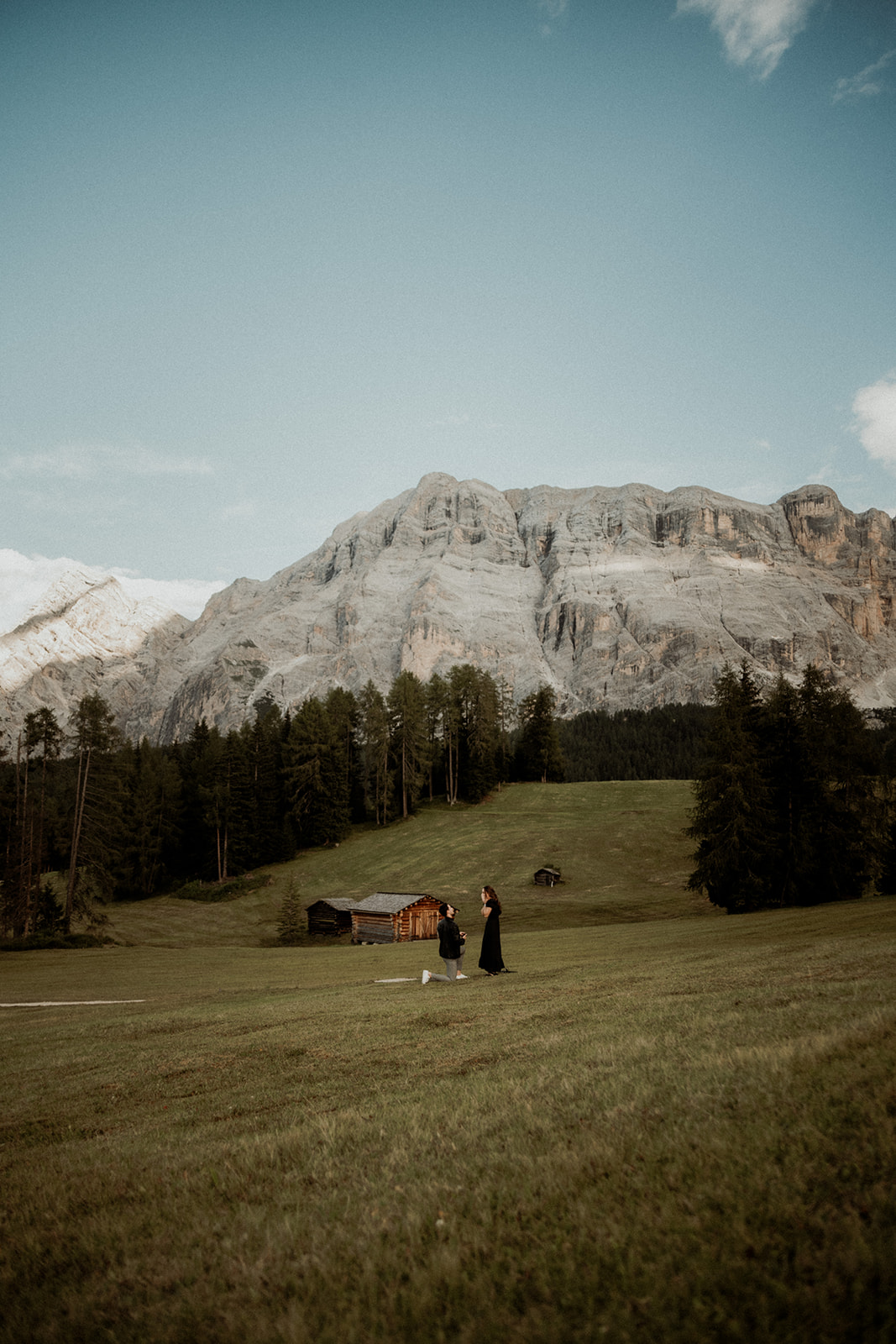 Heiratsantrag in den Bergen auf einer offenen und abgelegener Almwiese, Mann kniet nieder