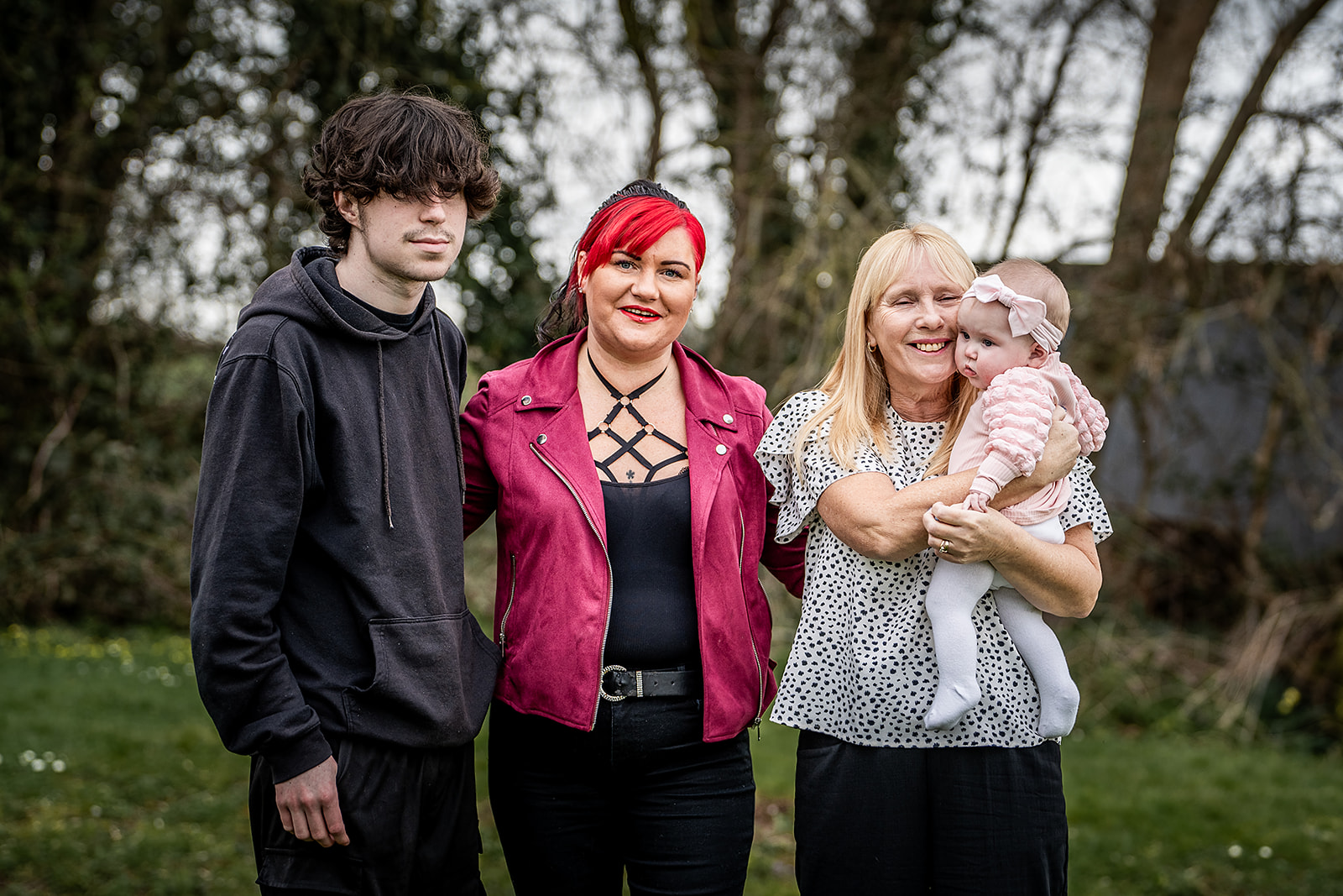 Four family members standing together, one holding a baby