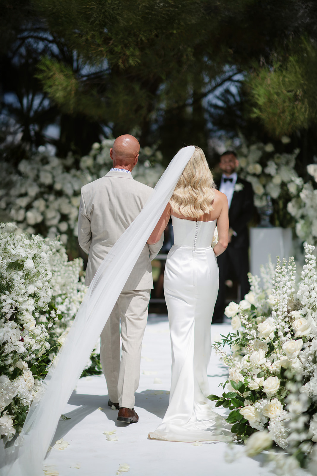 Bride and groom walking through a sunlit garden