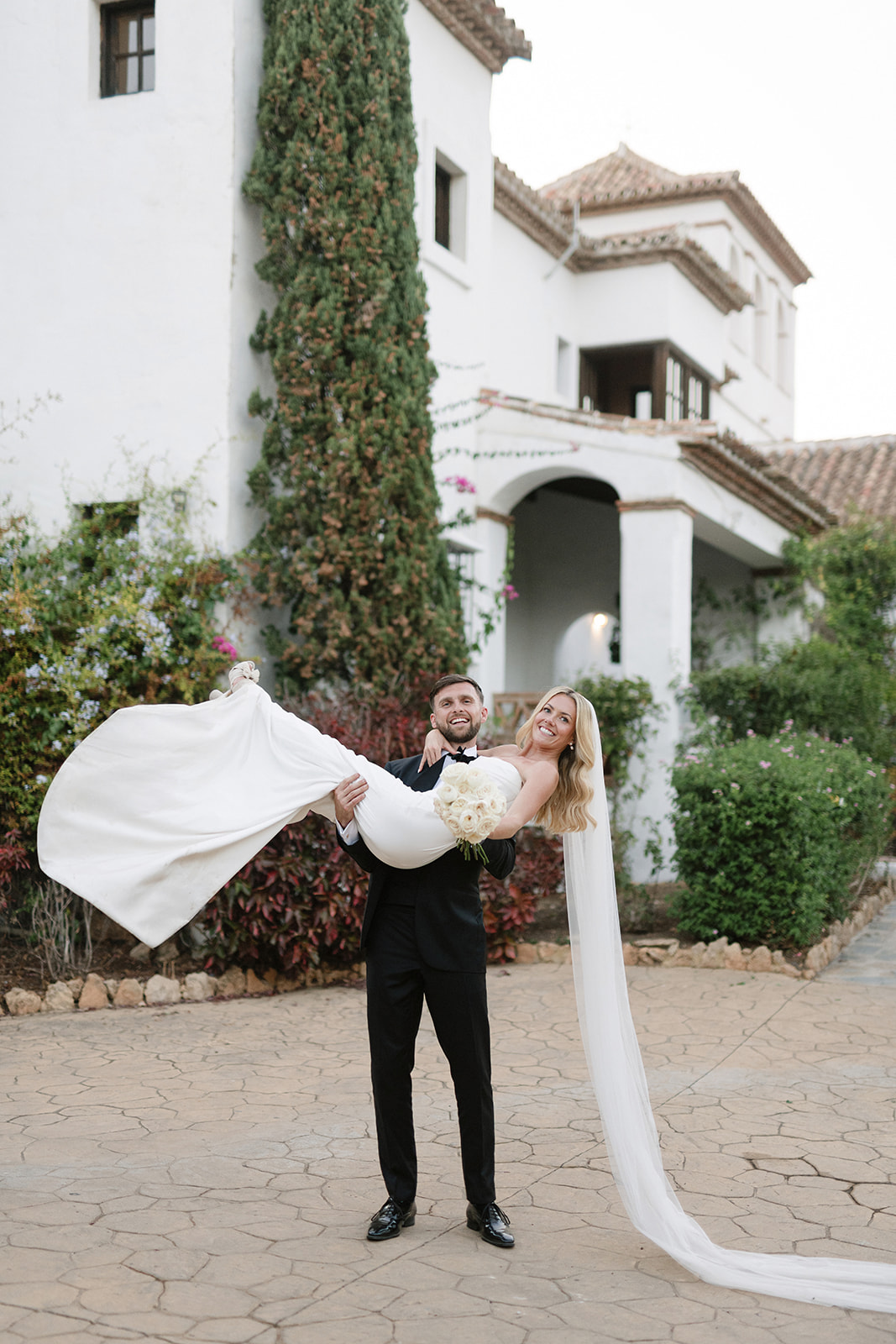 Bride and groom framed by a white arch at sunset in Mijas