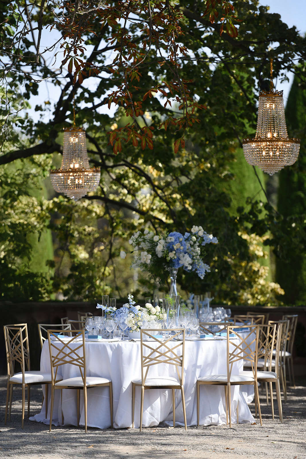 Crystal chandeliers over an outdoor dinner under the trees at Castell de Sant Marçal