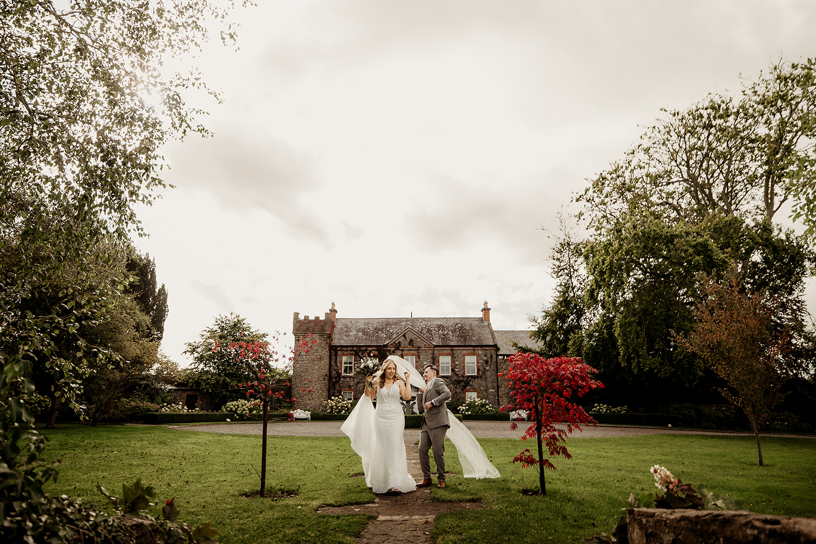 Edel and Oisin laughing in the gardens in front of Ballymagarvey Village’s manor house