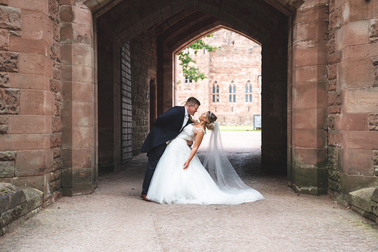 Emma and Jonny beneath a stone archway at Peckforton Castle