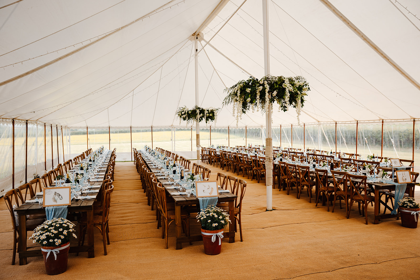 inside view of a Marquee with long trestle tables and chairs set up for a DIY farm wedding