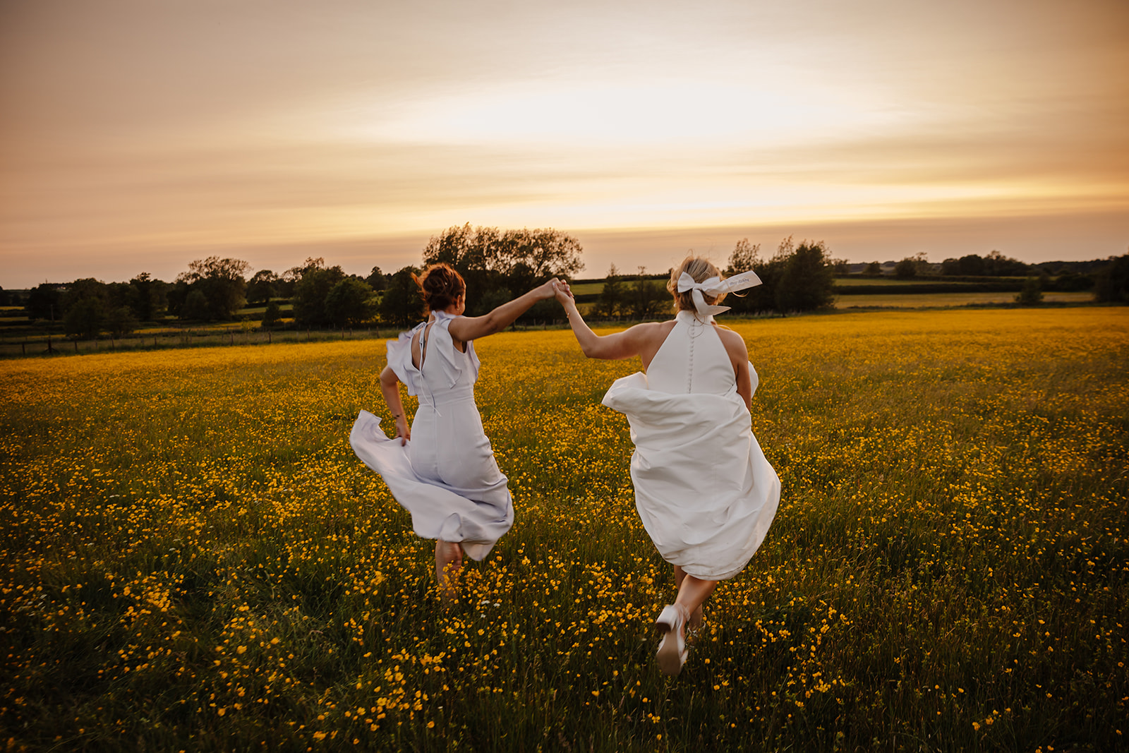 Farm wedding portraits running through buttercups at sunset