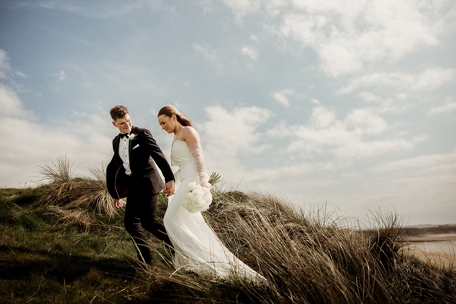 Alison and Ross walking hand in hand through the dunes