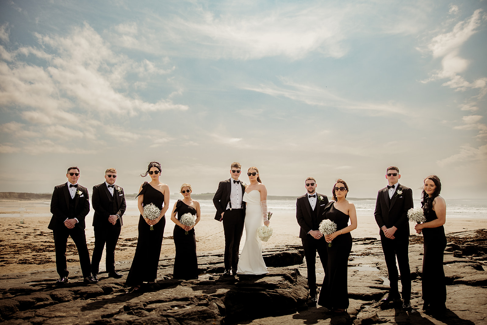 Alison, Ross and their wedding party on the rocky shore
