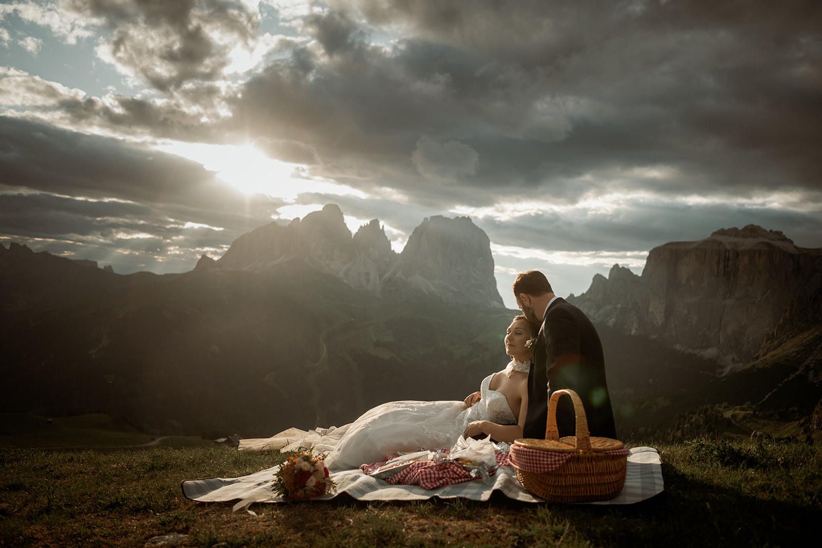 Sposarsi nelle Dolomiti – coppia che si coccola al tramonto durante un picnic all’aperto in montagna