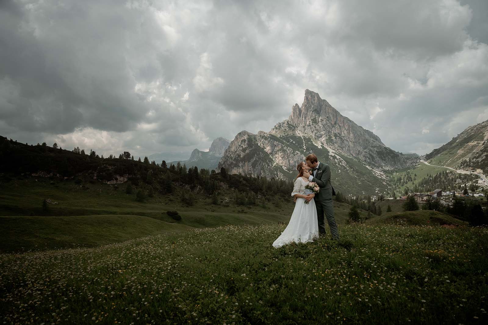 Sposarsi nelle Dolomiti – coppia che si bacia al centro di un prato con una vetta maestosa sullo sfondo