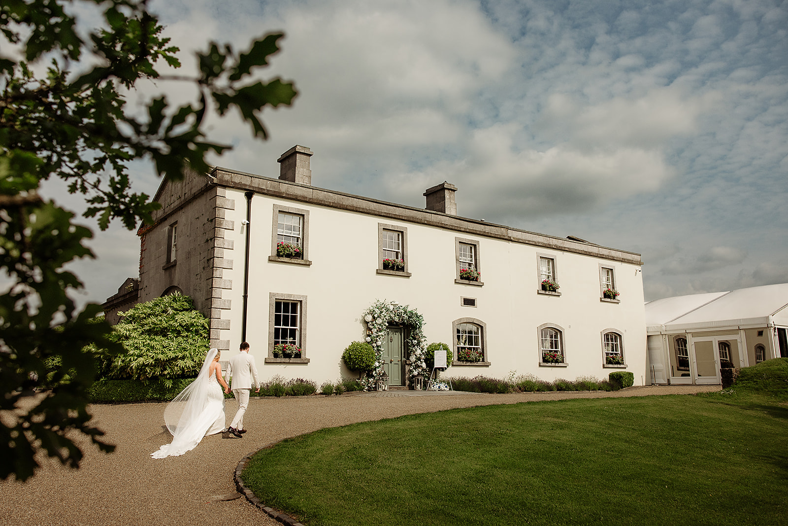 Megan and Jordan walking towards Clonabreany House after their wedding photographs.