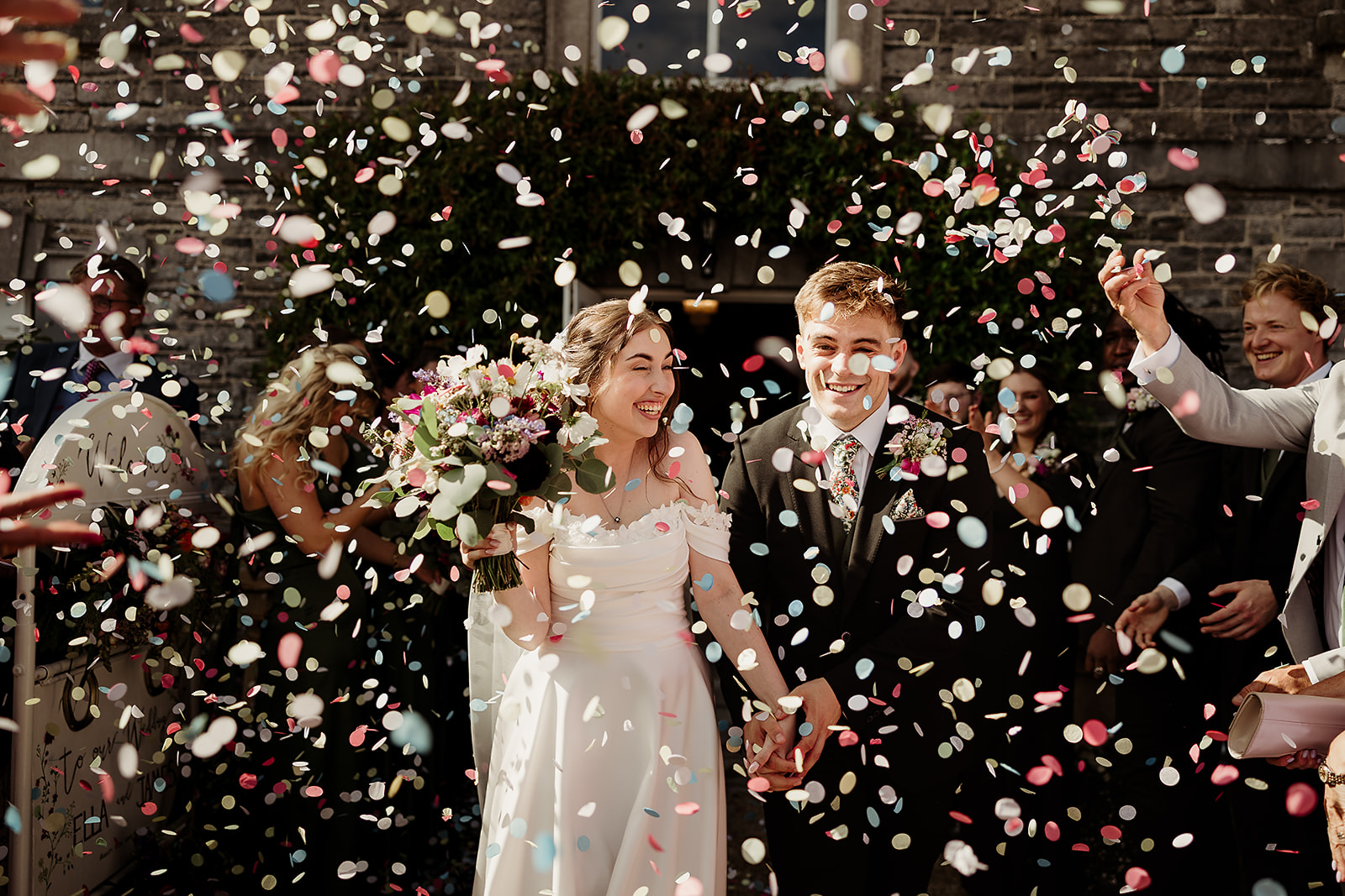 Ella and James walking through confetti outside The Millhouse in Slane