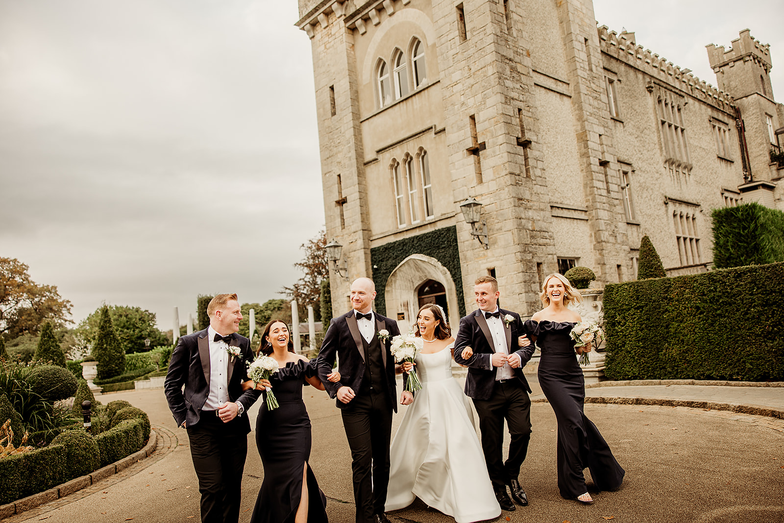 Emma and Conor laughing with their wedding party outside Cabra Castle