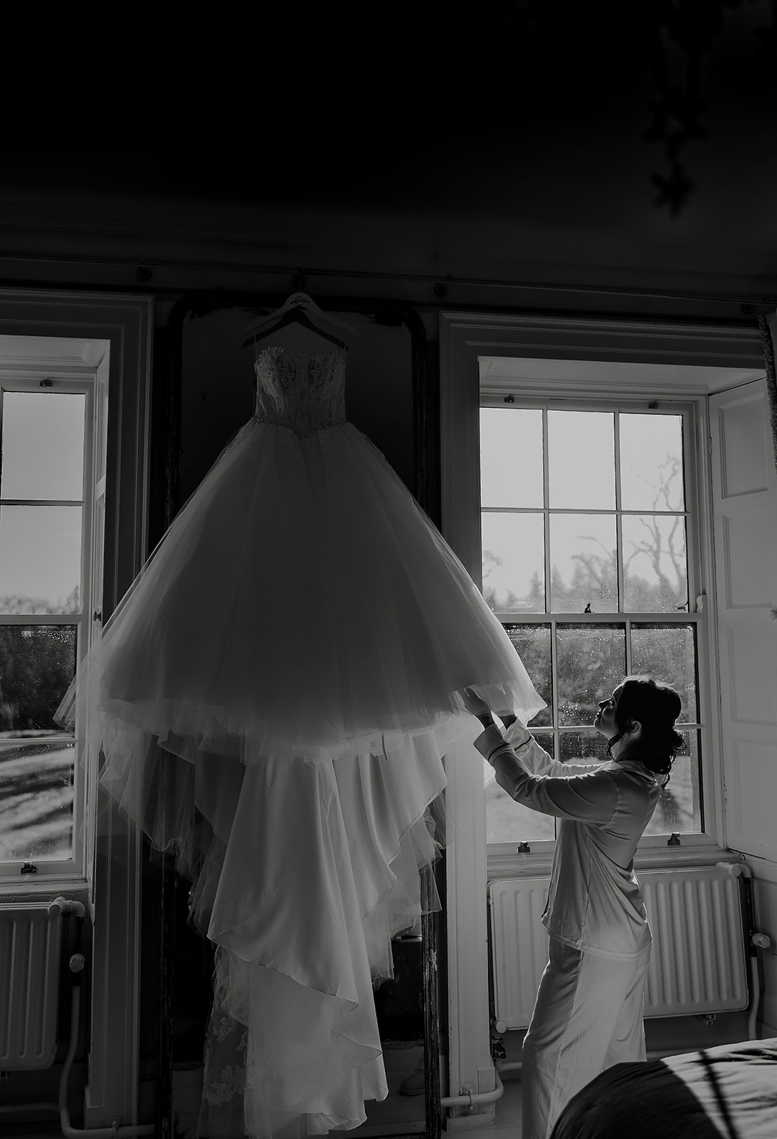 Jolene reaching for her wedding dress in window light