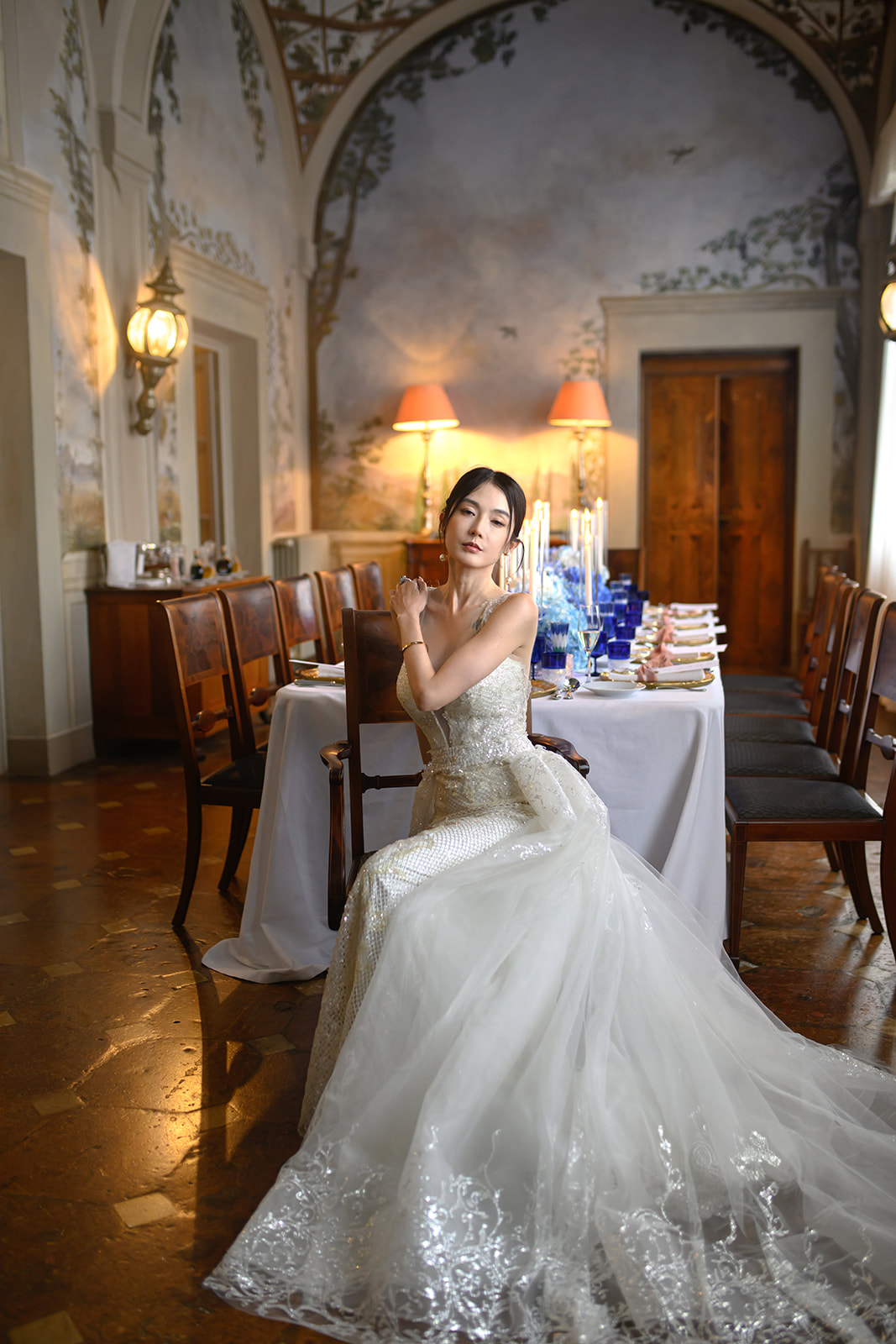 Bride seated in a candlelit frescoed dining room of a Tuscan villa