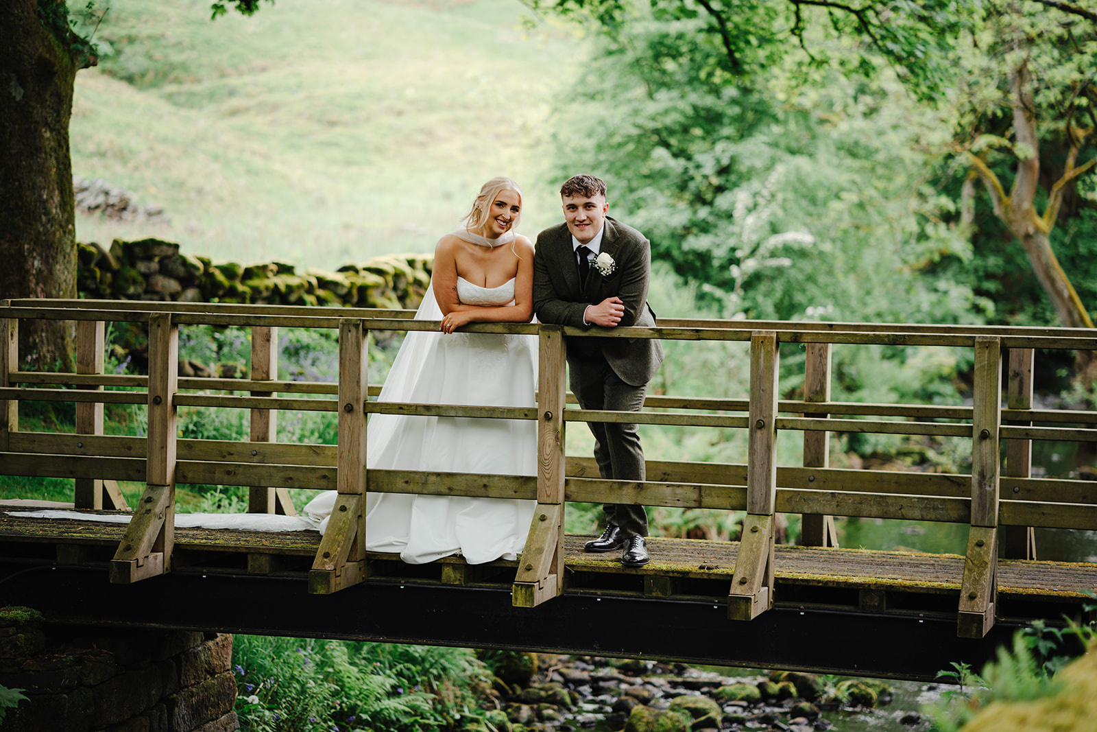 Claire and Joe smiling together on a wooden bridge at Ponden Mill