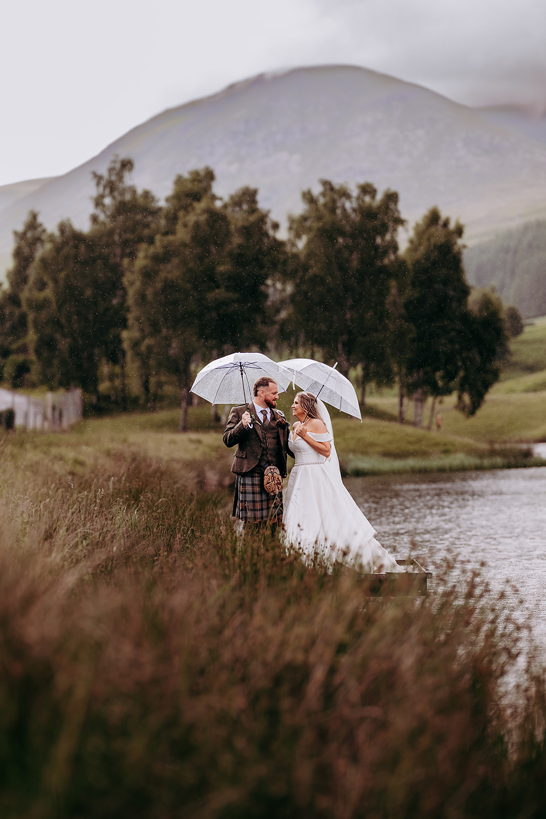 Claire and Callum together beneath clear umbrellas in the rain at Glen Clova