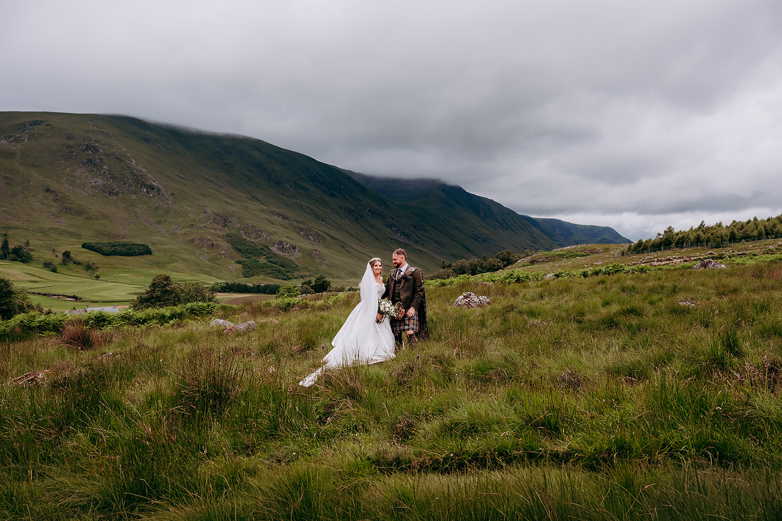 Claire and Callum beneath the moody Glen Clova sky on their wedding day