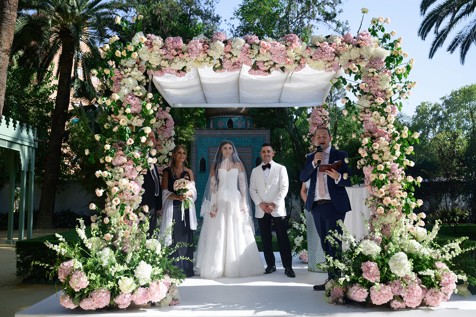 Wedding ceremony under a canopy of pink and white roses in a Seville garden