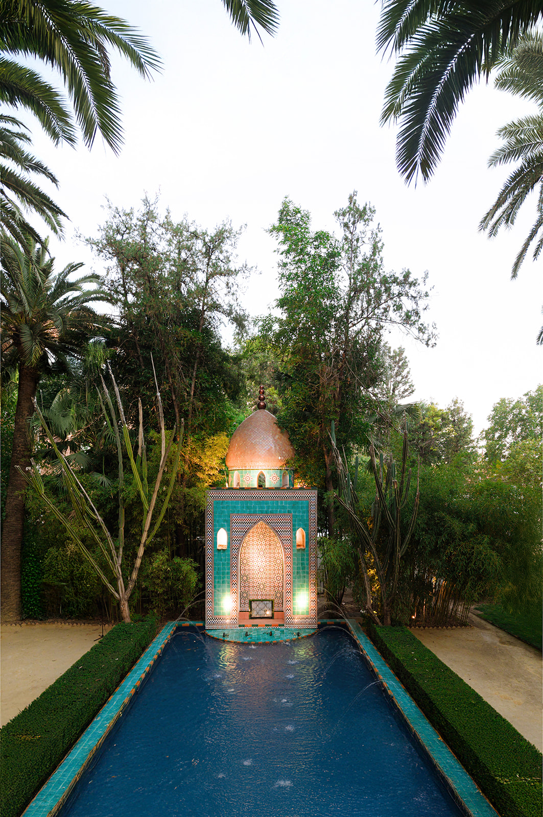 Andalusian garden with a long fountain and palms in Seville