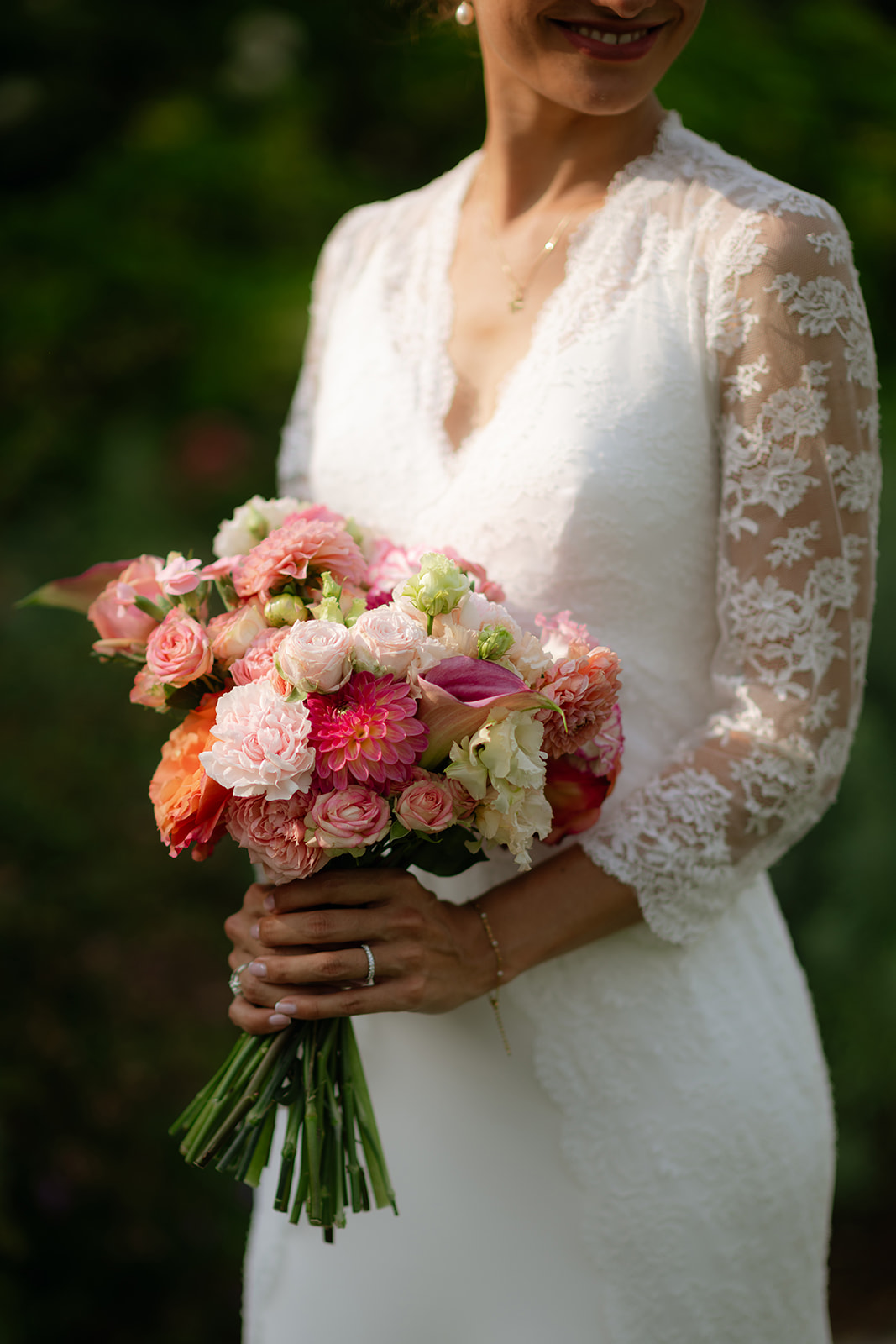 Editorial detail of the bride holding a bouquet of pink and peach roses