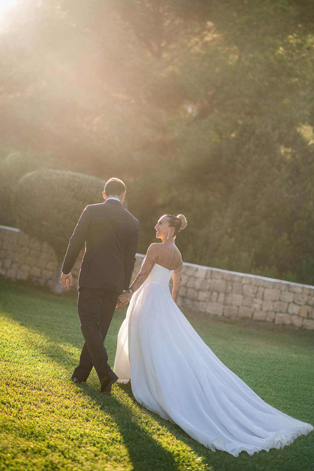 Bride and groom walking through a garden at golden hour in Ibiza