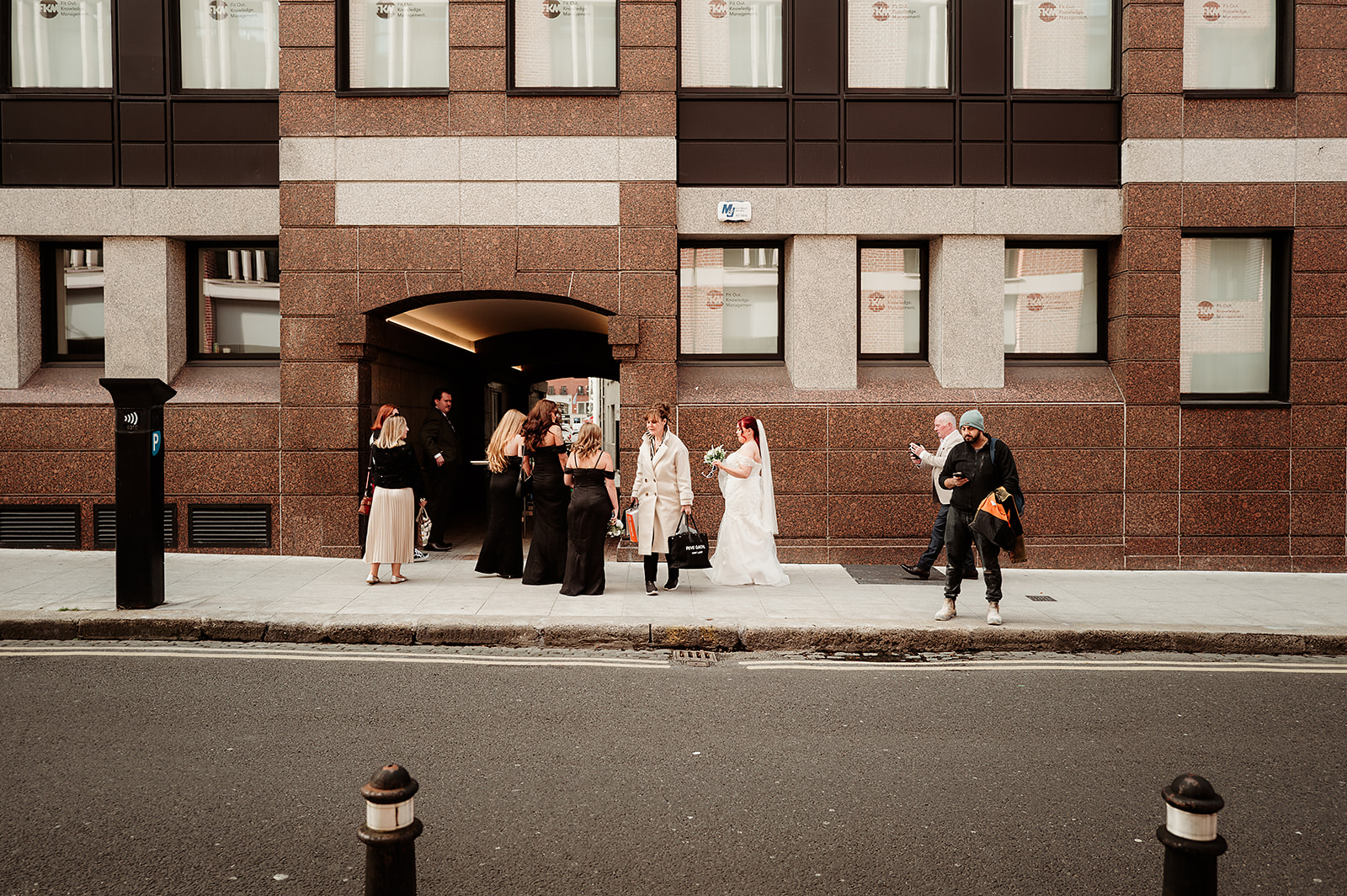 Aoife and her wedding party gathering on a Dublin pavement while city life continues around them