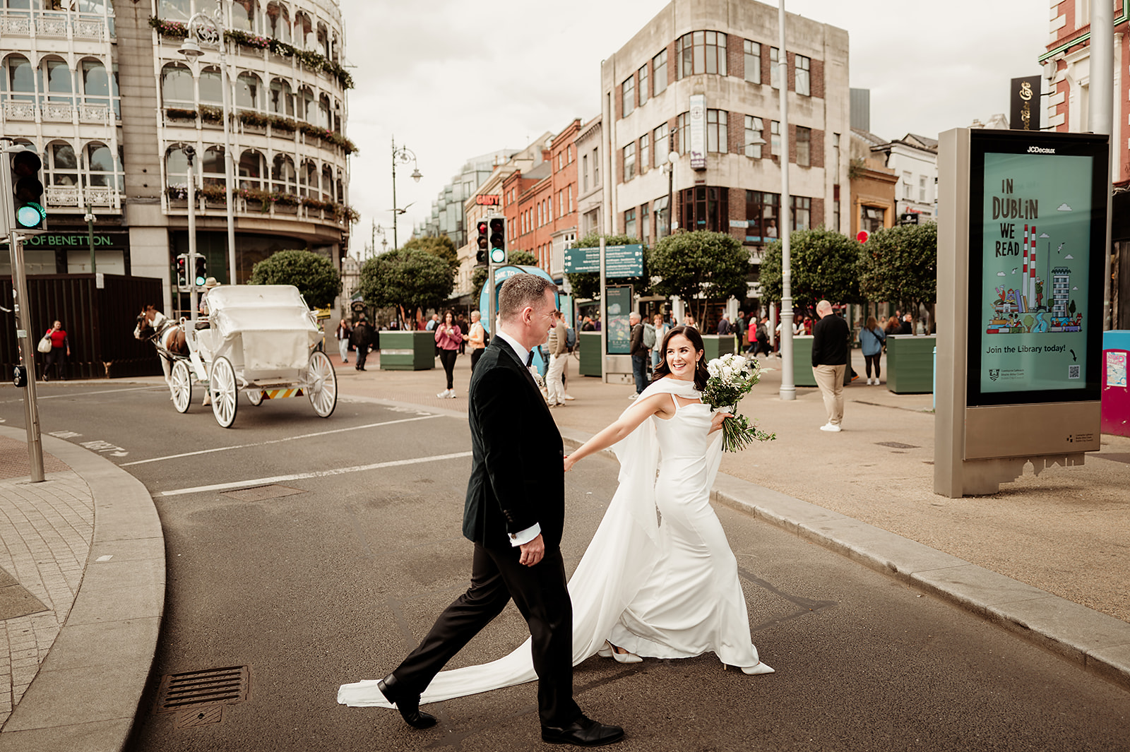 Rebecca and Louis smiling at each other as they cross a busy Dublin street