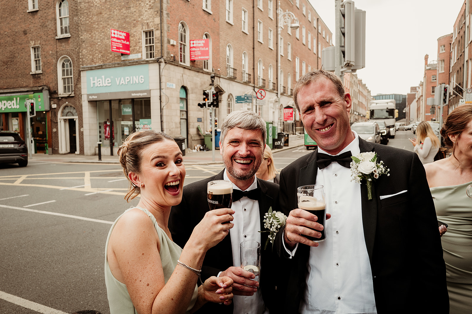 Wedding guests sharing a laugh and a drink on a Dublin street at Rebecca and Louis’s wedding